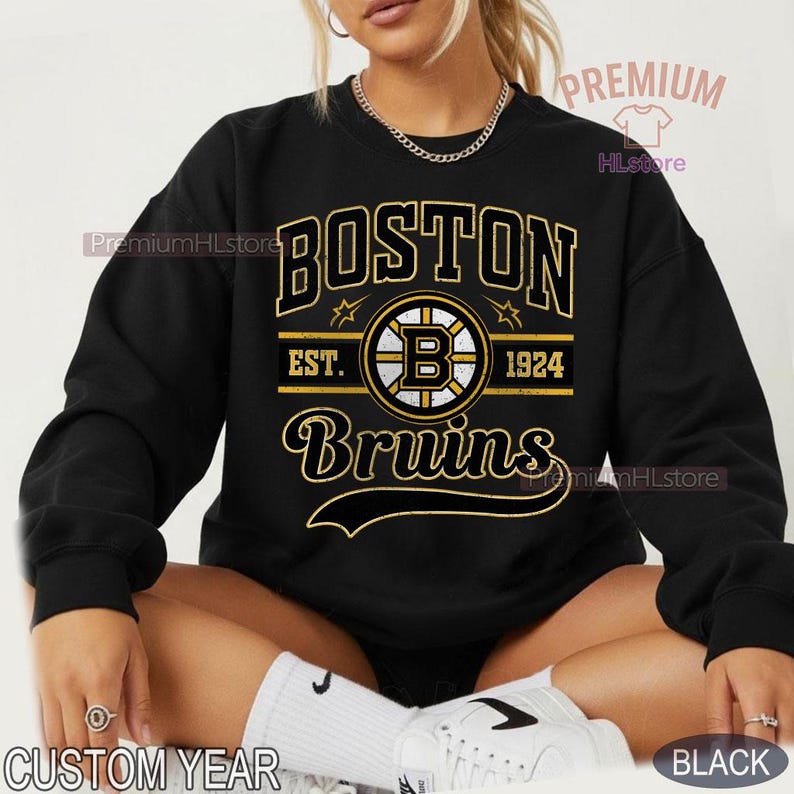 Puede incluir: Sudadera negra con el texto "BOSTON Bruins" en dorado y blanco, con el logotipo del equipo y "EST. 1924". La sudadera tiene cuello redondo y mangas largas. Tambi&eacute;n se ven las palabras "CUSTOM YEAR" y "BLACK".