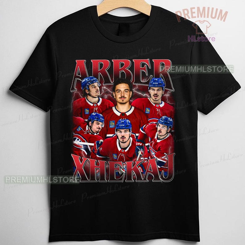 May include: Black t-shirt featuring a graphic of a hockey team with the names "ARBER" and "XHEKAJ" in red. The team is wearing red and blue uniforms. The shirt has a vintage, distressed look.