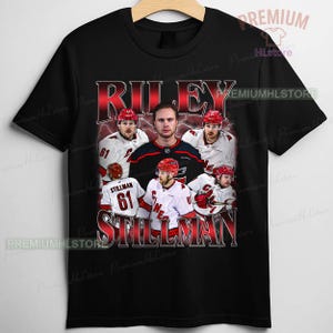 May include: Black t-shirt featuring a graphic design with the name "RILEY STILLMAN" in red, along with images of a hockey player in a red and white uniform. The shirt includes the number 61.