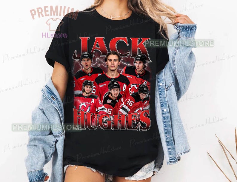 May include: Black t-shirt featuring a graphic of hockey players in red and black jerseys. The text "JACK HUGHES" is printed in red and white. The shirt has a vintage, distressed look.