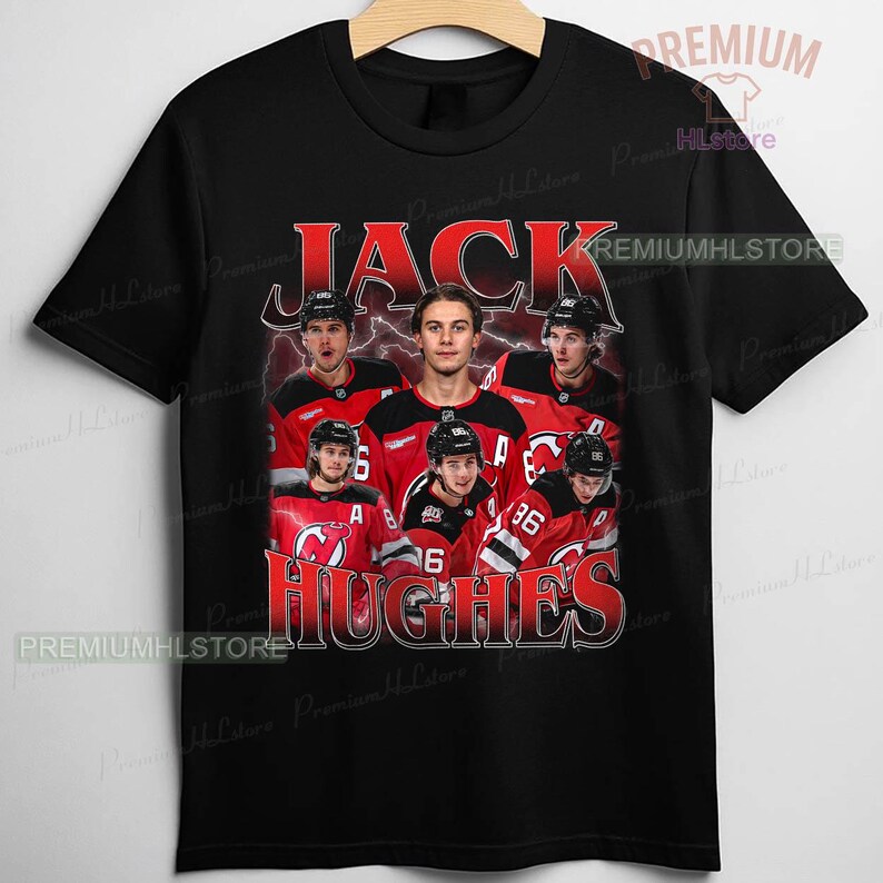 May include: Black t-shirt featuring a graphic of a hockey player and the name "JACK HUGHES" in red. The design includes a group of hockey players in their team uniforms. The shirt has a crew neck and short sleeves.