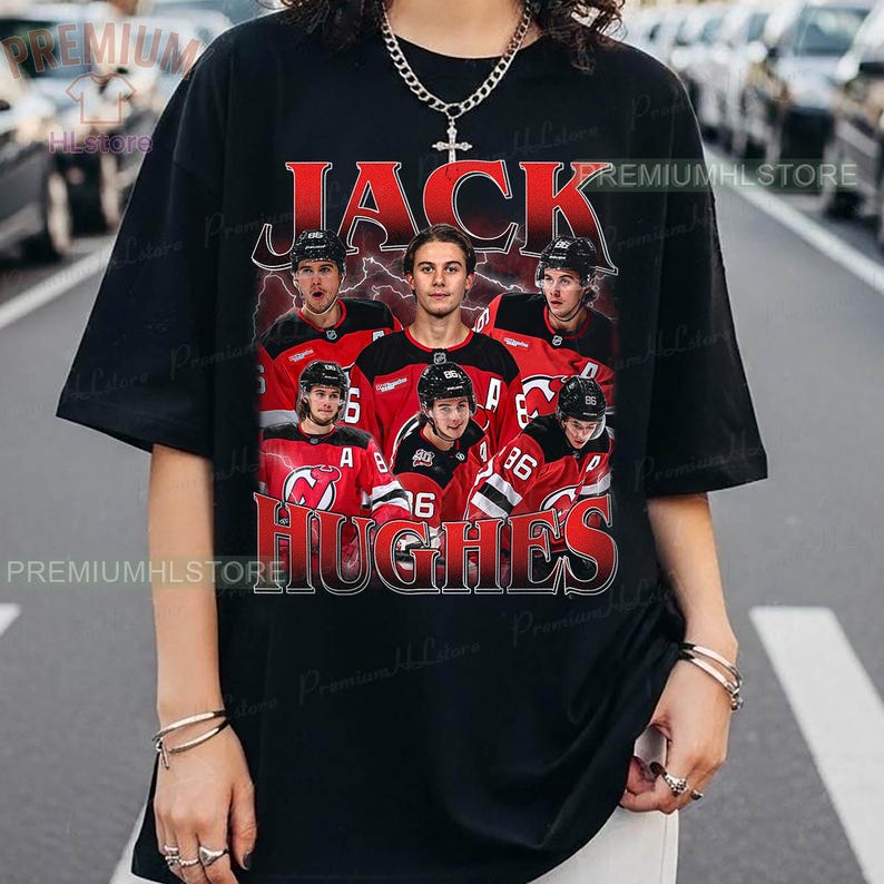 May include: Black t-shirt featuring a graphic of a hockey player with the name "JACK HUGHES" in red and white lettering. The design includes images of the player and other team members in red jerseys.