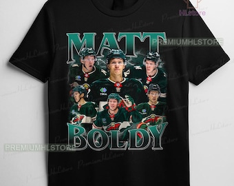 May include: Black t-shirt featuring a collage of hockey player Matt Boldy in a green and white uniform. The player's name is printed in teal, with the word "BOLDY" below. The shirt has a crew neck and short sleeves.