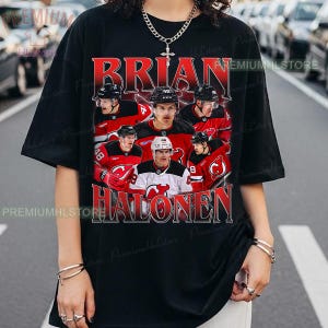 Könnte beinhalten: Schwarzes T-Shirt mit roter Grafik eines Eishockeyspielers, dem Namen "BRIAN HALONEN". Das Design beinhaltet mehrere Bilder des Spielers in seiner Hockeyuniform. Das T-Shirt hat kurze Ärmel und einen Rundhalsausschnitt.