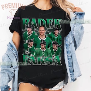 Może przedstawiać: Czarny t-shirt z grafiką hokeisty i napisem "Radek Faksa" w kolorze zielono-białym. Projekt zawiera zdjęcia zawodnika w zielono-białym stroju hokejowym. Koszulka ma okrągły dekolt i krótkie rękawy.