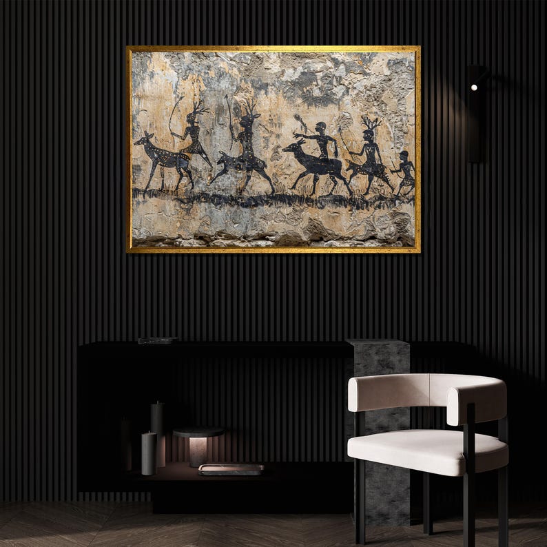 Pu&ograve; includere: Un'opera d'arte incorniciata con una cornice dorata raffigura una scena di pittura rupestre in bianco e nero. Figure con archi e frecce cacciano i cervi. L'opera d'arte &egrave; esposta sopra una consolle nera e una sedia bianca.
