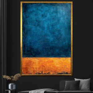 Könnte beinhalten: Abstrakte Malerei mit goldenem Rahmen. Das Kunstwerk hat eine strukturierte Oberfläche mit einem tiefblauen oberen Bereich und einem leuchtend orangefarbenen unteren Bereich. Die Farben erzeugen einen starken Kontrast und verstärken die visuelle Wirkung des Werks.