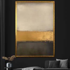 May include: Abstract artwork in a gold frame. The painting has a colour block design with a light beige upper section, a gold middle section, and a dark grey lower section. The artwork is displayed on a dark wall.