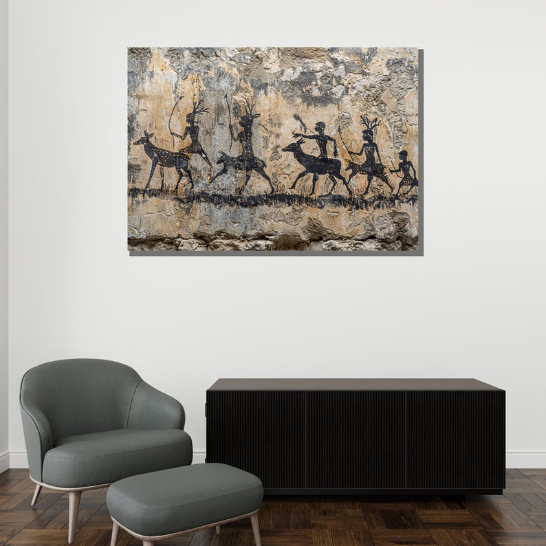 Pu&ograve; includere: Un'opera d'arte incorniciata raffigurante una scena di pittura rupestre nera di figure e cervi su uno sfondo strutturato beige e grigio. Le figure sembrano cacciare o essere in processione. L'opera d'arte &egrave; montata su una parete bianca sopra un mobile nero e una sedia grigia.