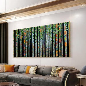 May include: A large rectangular canvas art piece depicting a stylized forest scene. Vertical black lines represent tree trunks, adorned with colorful circular patterns and green foliage. The artwork has a gold frame and hangs above a gray sectional sofa.