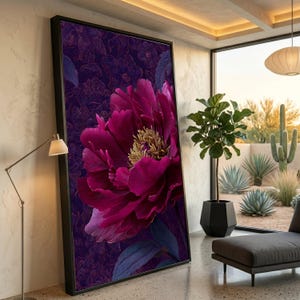 Op de afbeelding: Een groot ingelijst canvasdoek met een magenta pioenroos. De bloemblaadjes zijn gedetailleerd, met een gele kern en een donkerpaarse achtergrond. Het kunstwerk wordt gepresenteerd in een modern interieur, met een zwart frame.