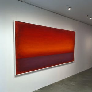 May include: Large rectangular abstract painting with a gradient of colors. The top portion is a deep red, transitioning to orange, and then a dark purple at the bottom. The artwork is framed in a white border and hangs on a white wall.