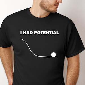 May include: A white ceramic mug with a black handle and the text "But First, Coffee" in a bold, black font. The mug is set against a blurred background, suggesting a cozy setting.