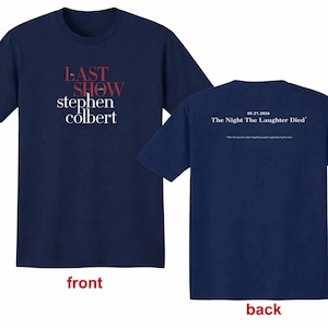 May include: Navy blue t-shirt with the text "LAST SHOW Stephen Colbert" on the front in white and red. The back of the shirt has the text "05.21.2026 The Night The Laughter Died" in white, with a smaller line of text below.