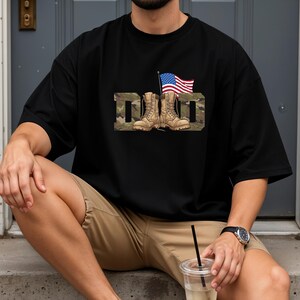 May include: Black t-shirt with the word "DAD" in a camouflage pattern, featuring combat boots and an American flag. The shirt is a relaxed fit, suitable for casual wear. The design is patriotic and celebrates fathers.
