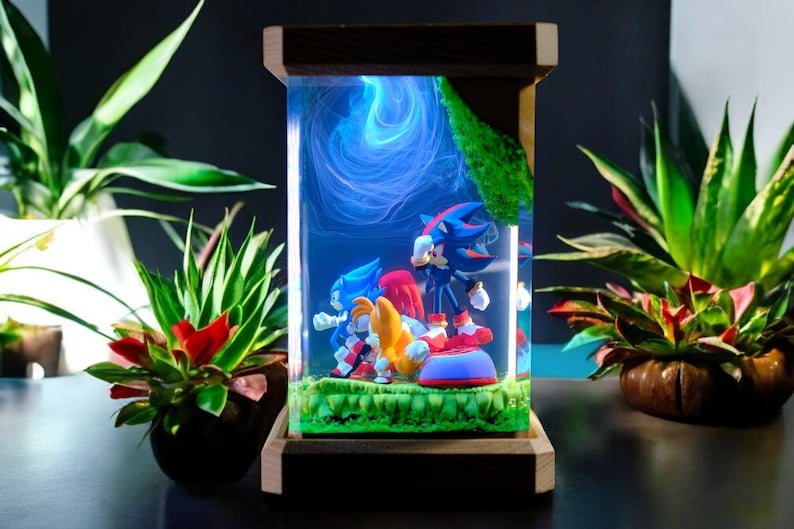 May include: A decorative resin display featuring Sonic the Hedgehog and friends. The figures are set in a clear, rectangular case with a wooden frame. The scene includes a blue swirling background and a green grassy base.