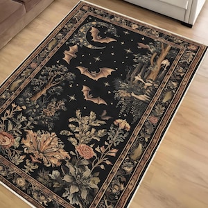 Op de afbeelding: Een rechthoekig zwart tapijt met een gedetailleerd ontwerp met vleermuizen, een halve maan, sterren en bloemen- en bos elementen. Het tapijt heeft een decoratieve rand met een crèmekleurige franje.