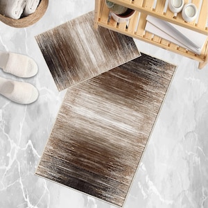 Può includere: Due tappetini da bagno rettangolari con un design a pennellate marroni e bianche. I tappetini sono posizionati su un pavimento a motivi marmorei, con un cestino di asciugamani bianchi e un paio di pantofole bianche.