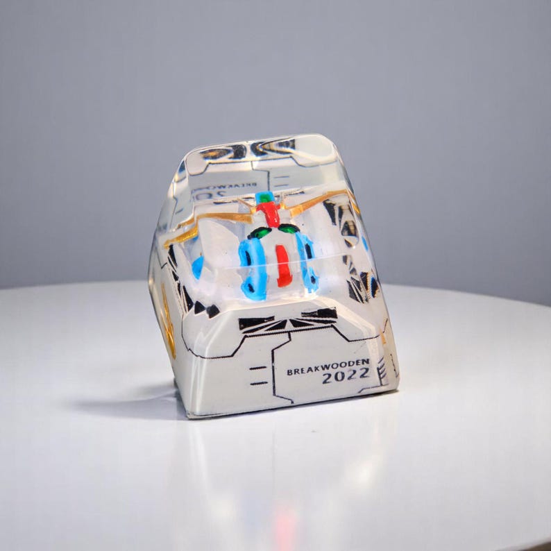 Peut inclure: Un objet rectangulaire en r&eacute;sine transparente avec un design d&eacute;taill&eacute;. L'objet pr&eacute;sente un int&eacute;rieur color&eacute; avec des accents bleus, rouges et dor&eacute;s. Le texte "BREAKWOODEN 2022" est visible sur le c&ocirc;t&eacute;.