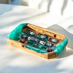 May include: A wooden tray with a teal resin inlay and compartments for holding small objects. The tray has a unique, irregular shape and is perfect for displaying small items.