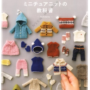 May include: A book cover titled DOLL KNIT BOOK 1/12 featuring a collection of miniature knitted doll clothing items including sweaters, hats, trousers, and accessories in various colours like blue, yellow, red, pink, and white arranged on a grey background.