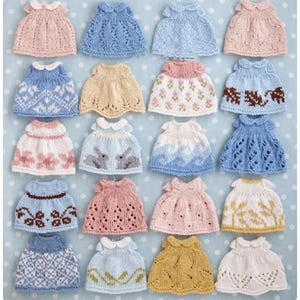 May include: A collection of twenty miniature knitted dresses arranged in a grid. Each dress features a unique pattern, including floral motifs, geometric shapes, animal silhouettes, and lace-like textures, with various pastel and neutral color palettes.