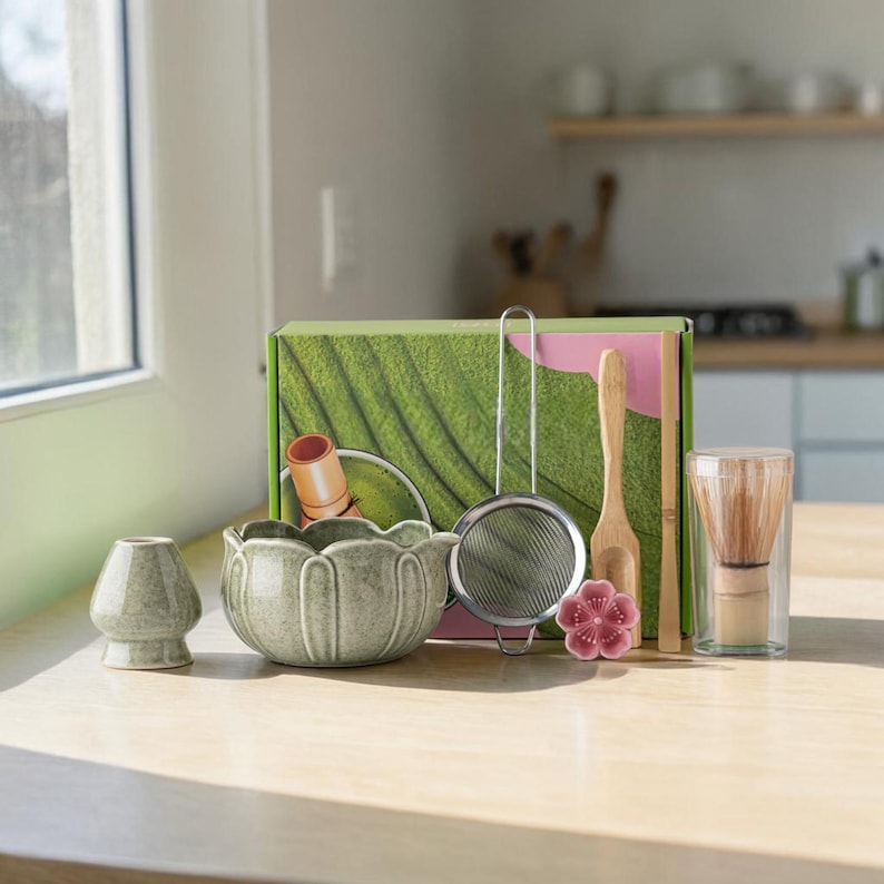 May include: A matcha tea set with a green ceramic bowl, whisk, and other accessories. The set includes a bamboo whisk, a sifter, a scoop, and a small ceramic stand. The box has a green leaf design.