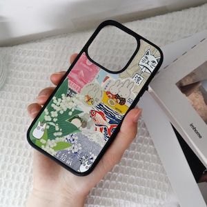 May include: Black phone case with a vibrant collage design featuring Japanese illustrations. The case includes images of rabbits, fish, flowers, and a cat. The case has a black border and a camera cutout.