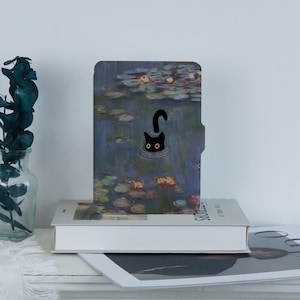 May include: A black cat peeks out of the water in a painting of water lilies. The painting is on a blue and purple background with green lily pads and pink flowers. The cat's eyes are yellow.