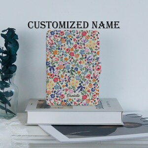 May include: A floral patterned case with the name "Danielle" printed on the front. The case features a colorful design with flowers in shades of pink, blue, yellow, and white. The text "CUSTOMIZED NAME" is printed at the top.