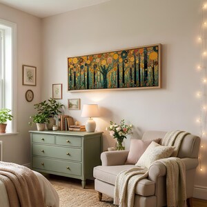 May include: A long rectangular wall art piece featuring a stylized forest with circular golden and orange foliage, framed in light wood. The artwork hangs above a sage green wooden dresser with brass knobs and a white table lamp in a room.