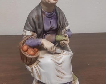 Estatueta vintage de porcelana artesanal representando uma senhora com cesta.
