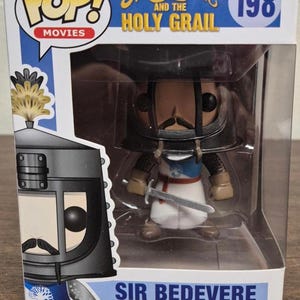 Puede incluir: Figura de vinilo Funko Pop! de Sir Bedevere de Monty Python y el Santo Grial. La figura está en una caja transparente y presenta a Sir Bedevere con su armadura, sosteniendo una espada. La caja tiene el logo de Pop! Movies y el número 198.