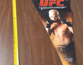 Puede incluir: Un banderín de la UFC con forma de banderín con Tito Ortiz. El banderín tiene imágenes de Ortiz y el logotipo de la UFC. El banderín mide aproximadamente 76 cm de largo.