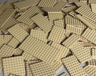 May include: A pile of tan-colored building baseplates with a grid of circular studs. The plates are rectangular and vary in size, suitable for constructing various structures. The image shows a collection of toy construction components.