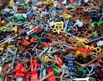 May include: A large collection of assorted plastic building block accessories including miniature bows, crossbows, swords, spears, and various tools in a wide array of colors such as red, brown, gray, yellow, blue, green, and black.
