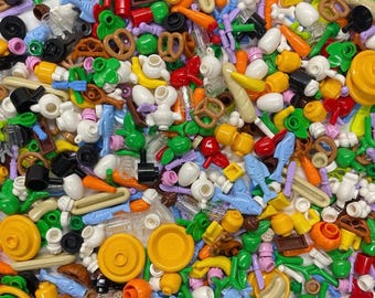 May include: A large collection of assorted plastic building block accessories in various colors, including miniature food items like pretzels, bananas, and fish, alongside small kitchenware, tools, and structural components scattered together.
