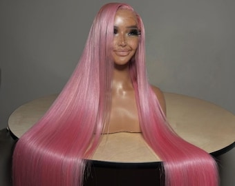 May include: A long, straight pink wig displayed on a mannequin head. The wig features a natural-looking hairline and a vibrant, solid pink color. The hair is sleek and appears to be made of high-quality synthetic fibers, with a glossy finish.