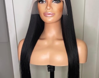 May include: A long, straight, jet-black wig displayed on a mannequin head. The wig features a center part and a sheer lace front panel that extends across the forehead, designed to mimic a natural hairline with visible lace mesh detailing.