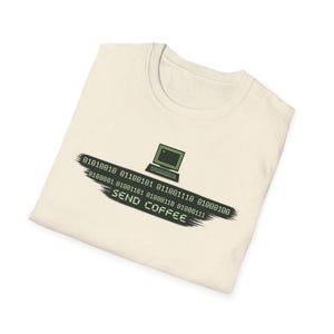 Könnte beinhalten: Cremefarbenes T-Shirt mit einer grün-schwarzen Grafik. Das Design zeigt ein Laptop-Symbol und Binärcode über den Worten "SEND COFFEE" in grüner Schrift. Das T-Shirt ist gefaltet.