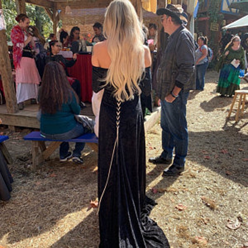 May include: A black velvet maxi dress with a lace-up back detail. The dress has long sleeves and a flowing skirt.