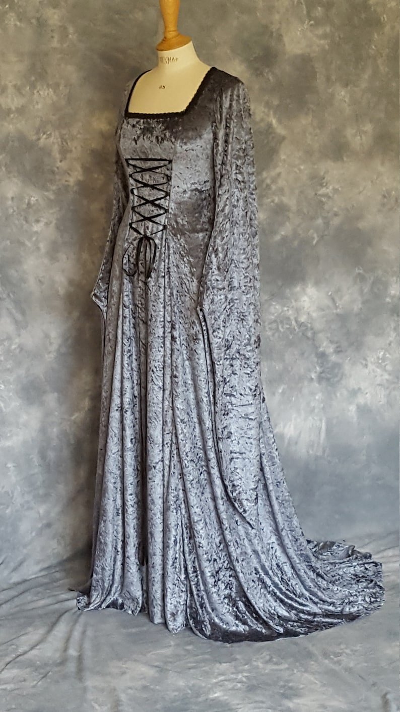 K&ouml;nnte beinhalten: Ein langes, silbergraues Samtkleid mit Schn&uuml;rbrust und langen &Auml;rmeln. Das Kleid hat einen flie&szlig;enden Rock und einen Schlepp.