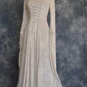 K&ouml;nnte beinhalten: Ein wei&szlig;es Samtkleid mit einem Schn&uuml;rkorsett und langen &Auml;rmeln. Das Kleid hat einen flie&szlig;enden Rock und ist perfekt f&uuml;r eine mittelalterliche oder Fantasy-Veranstaltung.