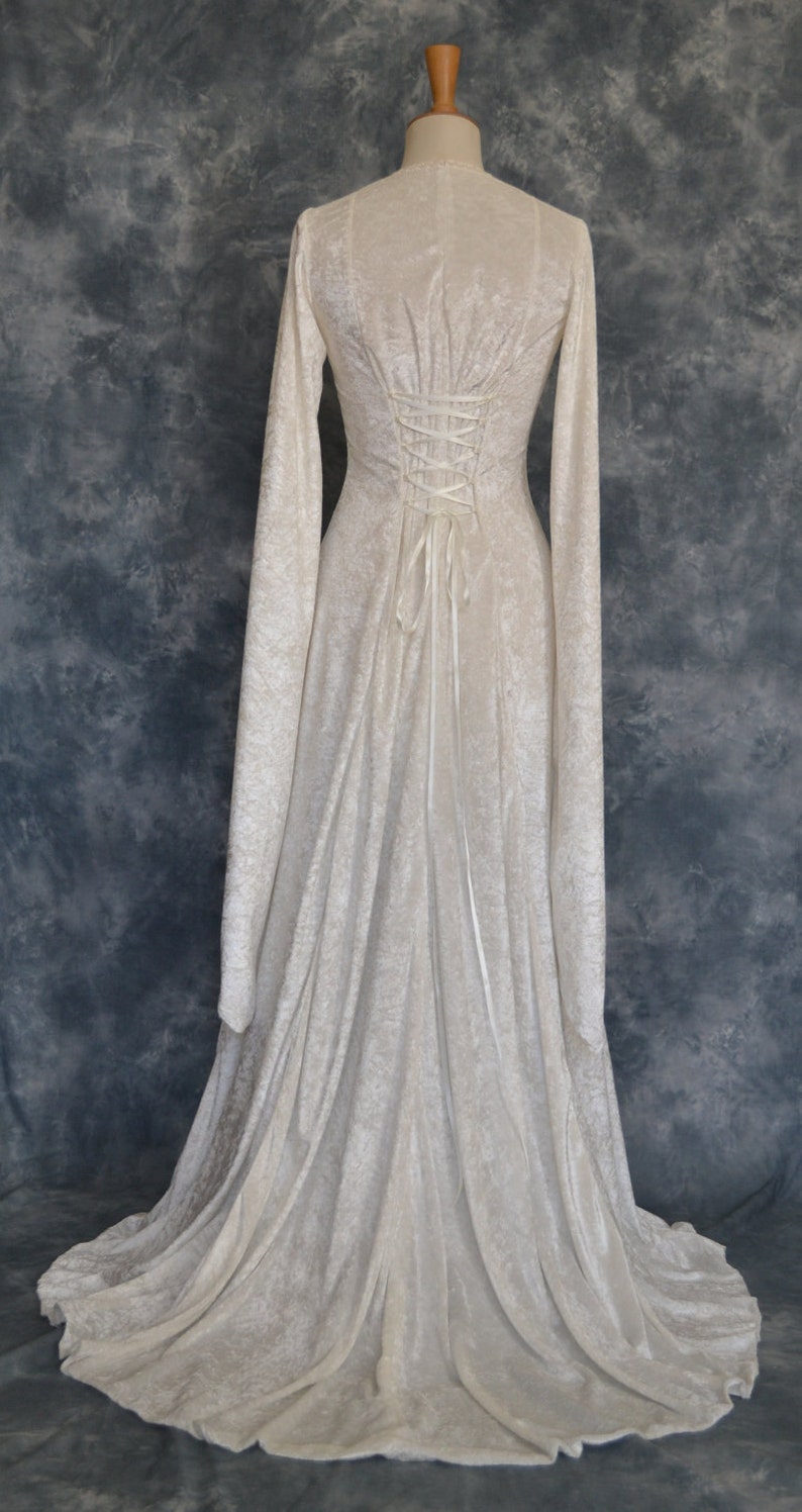 K&ouml;nnte beinhalten: Ein wei&szlig;es Samtkleid mit langen &Auml;rmeln und einem Schn&uuml;rr&uuml;cken. Das Kleid hat einen flie&szlig;enden Rock und ist perfekt f&uuml;r einen formellen Anlass.