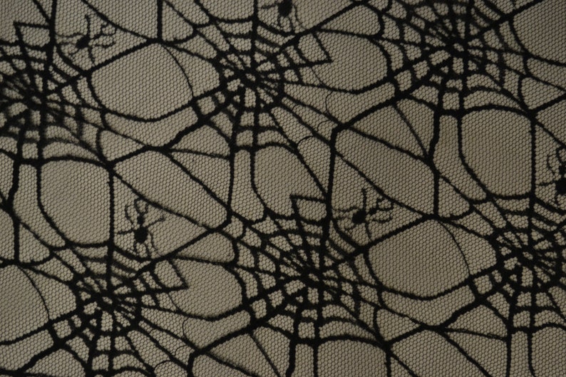 May include: Black spiderweb lace fabric with a subtle texture. The fabric has a repeating pattern of spiderwebs with small spiders in the corners.