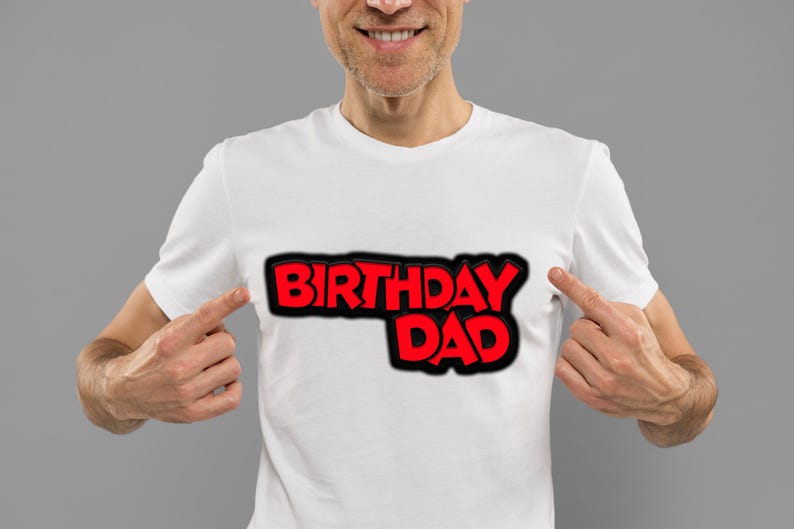 K&ouml;nnte beinhalten: Ein wei&szlig;es T-Shirt mit dem Aufdruck "Birthday Dad" in roten und schwarzen Buchstaben.