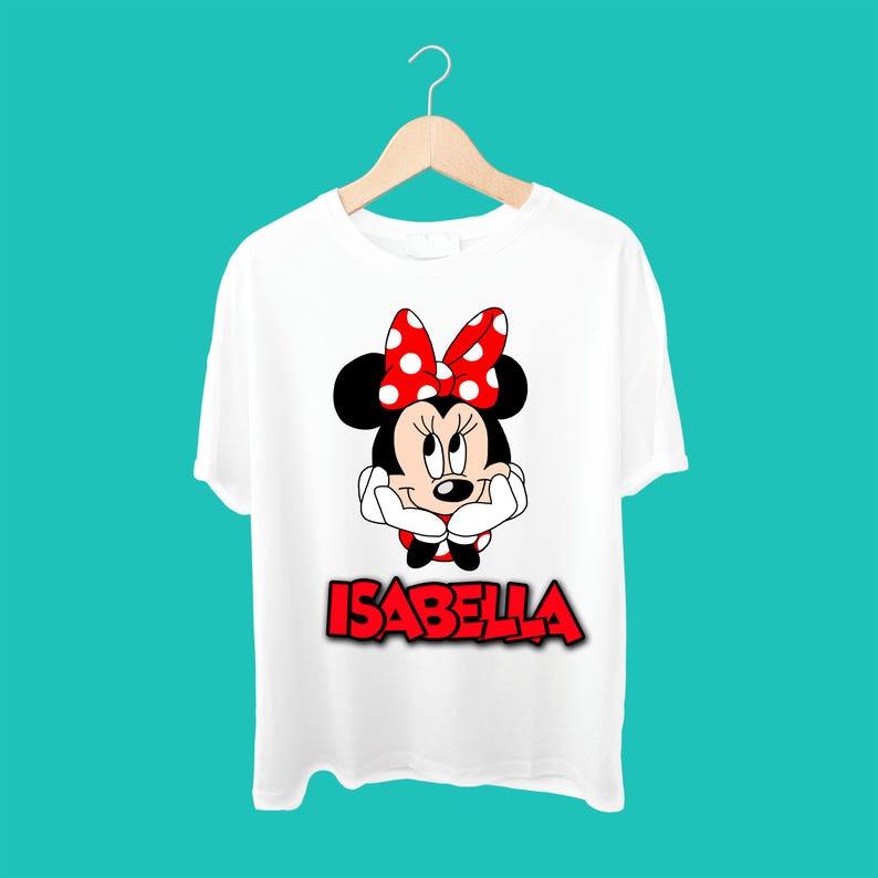 K&ouml;nnte beinhalten: Wei&szlig;es T-Shirt mit einer roten Schleife mit wei&szlig;en Punkten, einem Cartoon-Bild von Minnie Mouse und dem Namen "Isabella" in Rot.