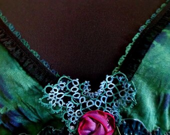 May include: A green and blue silk top with black lace trim and a delicate blue and green lace flower embellishment.