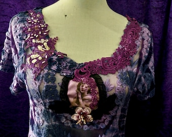 May include: A purple and blue lace top with a floral design and a beaded embellishment. The top has a scoop neck and short sleeves.