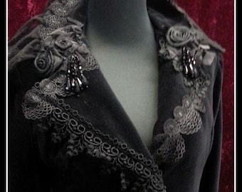 May include: A black velvet jacket with a high collar featuring intricate lace and beaded embellishments.